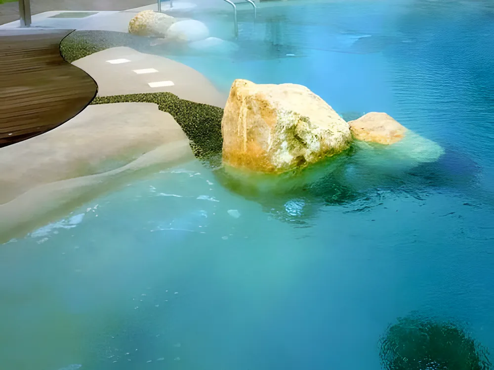 BIOdesign-Pool mit klarem, türkisem Wasser und Natursteinen