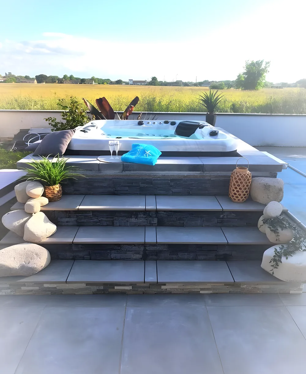 Aufgebauter Whirlpool auf einer Terrasse mit Treppe und Blick über die Felder